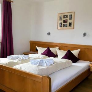 Doppelbett mit lila Kissen und heller Holzeinrichtung - Ferienwohnung (#16)