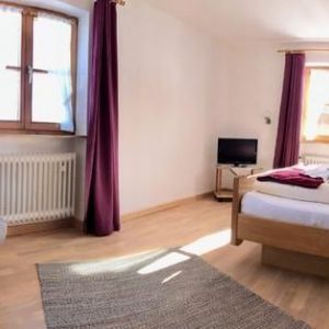 Helles Schlafzimmer mit Doppelbett und weinroten  Vorhängen - Ferienwohnung (#16)